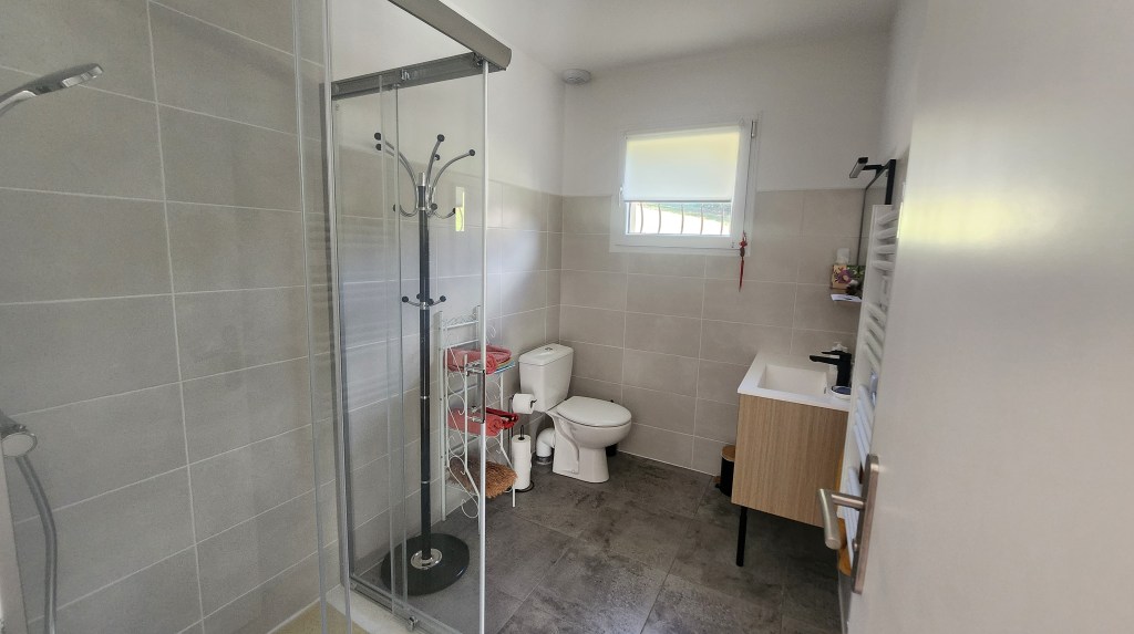 Salle de bain moderne avec douche, toilettes et lavabo en bois.